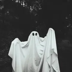 Figura fantasmal blanca con dos agujeros negros para ojos, en un bosque oscuro. ¿Qué significa soñar con fantasmas?