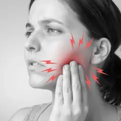 Mujer con dolor de muelas, tocándose la mejilla. Rayos rojos indican el dolor. ¿Qué hacer para el dolor de muelas?