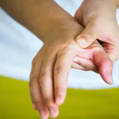 Mano con dolor en el pulgar, buscando alivio y soluciones sobre como curar la rizartrosis del pulgar.