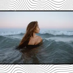 Mujer con cabello largo y ondulado se sumerge en el mar, rodeada de olas que parecen invitar a soñar con olas gigantes.