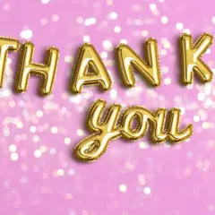Globos dorados forman las palabras de agradecimiento "Thank you!" sobre un fondo rosa con luces bokeh.