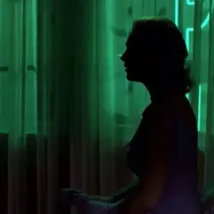 Silueta de mujer en perfil, con cortinas verdes y veo sombras negras que se mueven.
