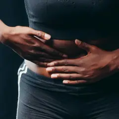 Manos sobre el abdomen, buscando alivio. Descubre 11 trucos para acabar con los gases y la tripa hinchada.