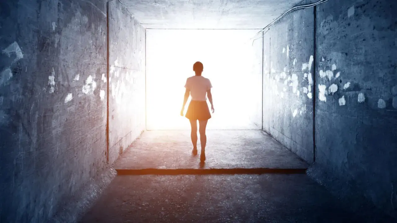 Una mujer camina hacia la luz en un túnel, como si soñara con tu madre fallecida.