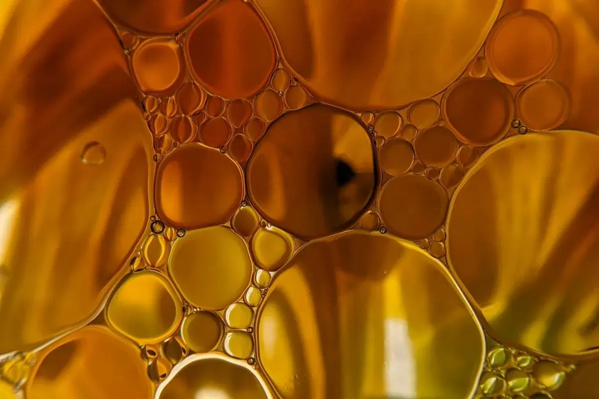 Gotas doradas y ámbar flotan juntas, creando un patrón hipnótico que te hace soñar con aceite.