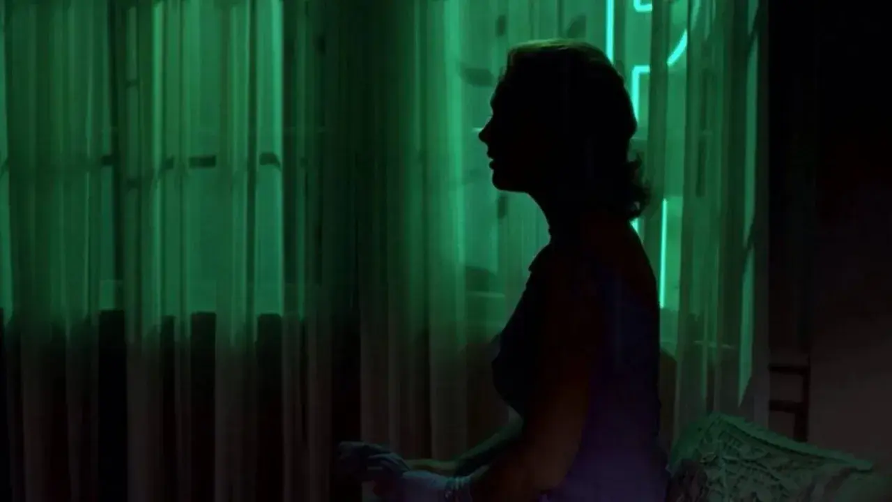 Silueta de mujer en perfil, con cortinas verdes y veo sombras negras que se mueven.