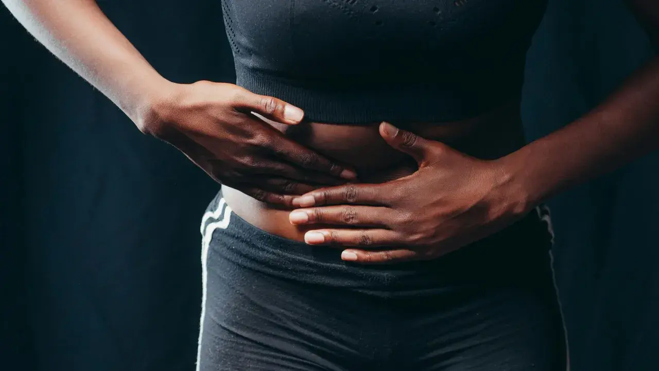 Manos sobre el abdomen, buscando alivio. Descubre 11 trucos para acabar con los gases y la tripa hinchada.