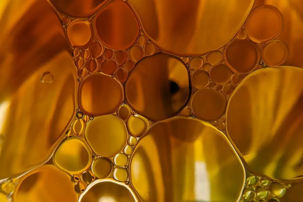 Gotas doradas flotan en un líquido, creando un patrón hipnótico que te hace soñar con aceite.