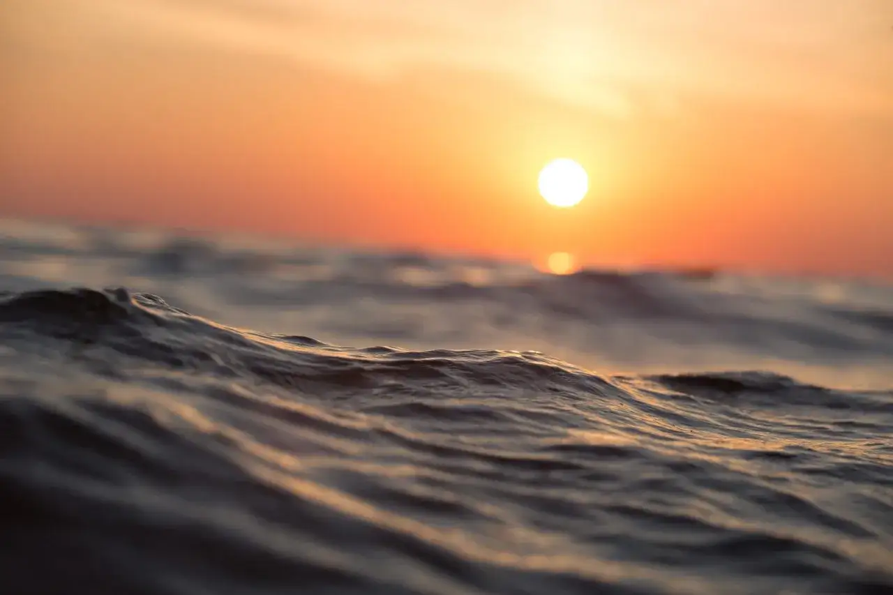 Olas suaves reflejan el atardecer anaranjado. Un momento para soñar con agua de mar y la calma que trae.